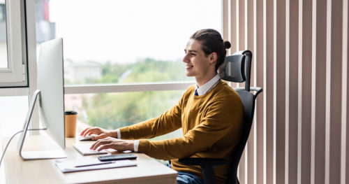 Young adult male professional in office performing computer programming.