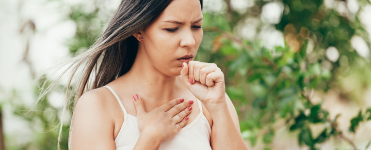 woman coughing into her hand