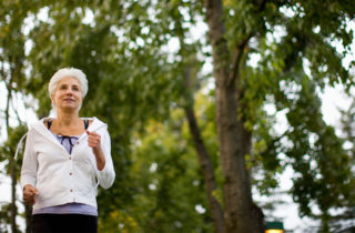 Senior woman with chronic condition jogging outdoors.