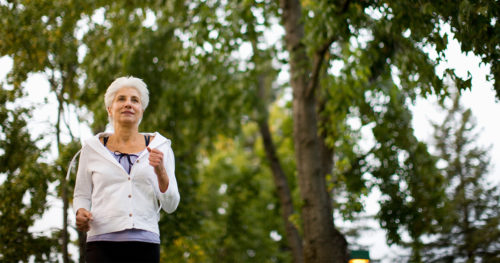 Senior woman with chronic condition jogging outdoors.