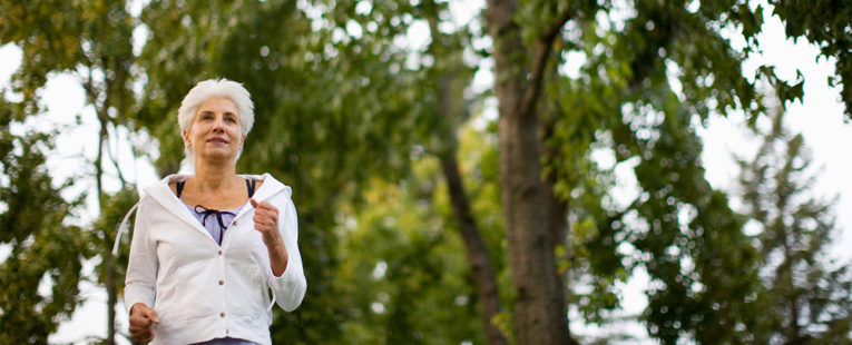 Senior woman with chronic condition jogging outdoors.