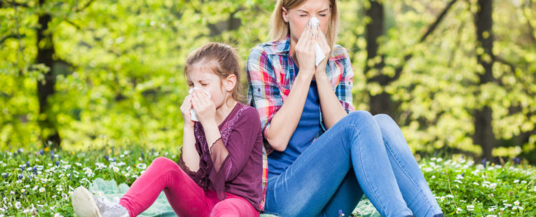 a small girl and a woman suffer with allergies outside
