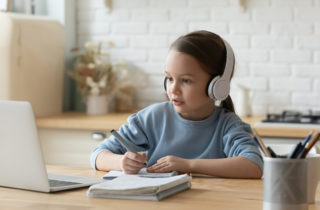 Young girl student engaged in virtual learning on laptop at home.