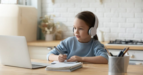 Young girl student engaged in virtual learning on laptop at home.