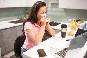female officer worker blowing her nose at her cubicle