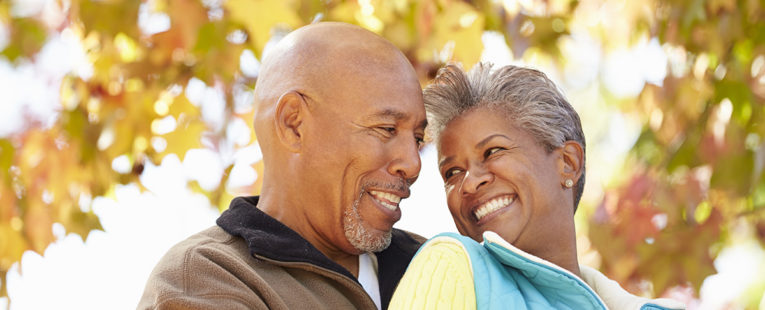 Active African-American senior couple in a warm embrace on an autumn day.
