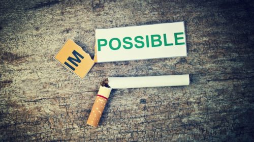 cigarette broken in half next to an impossible sign ripped to read possible