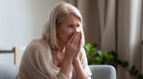 concerned senior woman holding her hands to her face