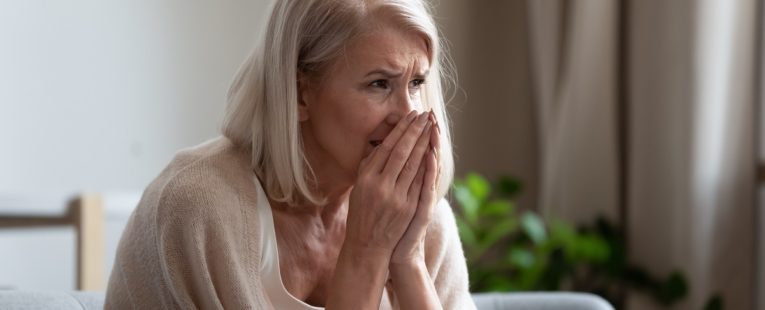 concerned senior woman holding her hands to her face