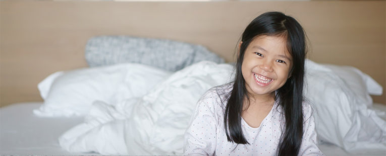 Young Asian-American girl waking up after a restful night's sleep