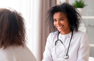 female doctor smiles as they meet with a female patient