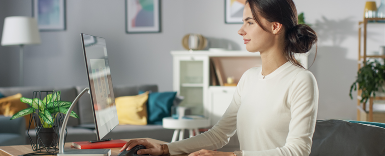 woman sits upright in a home office demonstrating proper posture, ergonomic desk setup