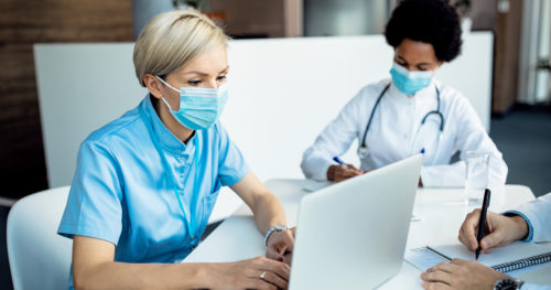 masked care team members work on laptops
