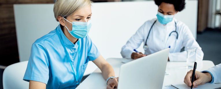 masked care team members work on laptops