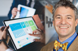 Formally dressed faceless woman using tablet computer exploring charts while sitting at table in office during business meeting with colleagues