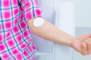 Female patient flexing arm after blood work in health care provider's office.