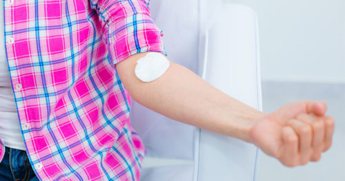 Female patient flexing arm after blood work in health care provider's office.