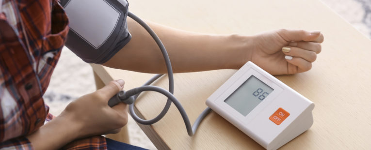Young woman measuring his blood pressure at home