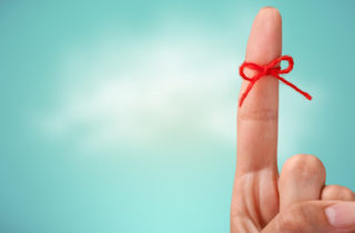 index finger with a red ribbon tied around it