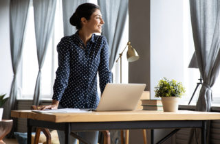woman standing over her laptop on a desk