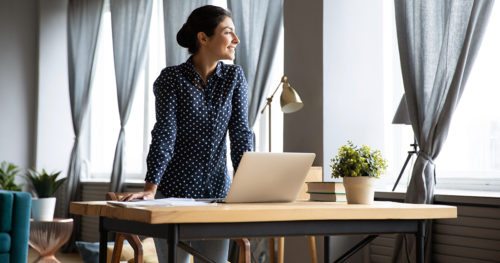 woman standing over her laptop on a desk