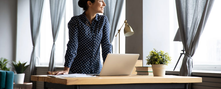 woman standing over her laptop on a desk