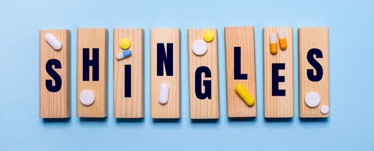 The word "shingles" is spelled out on wooden tiles with medicine placed on top.