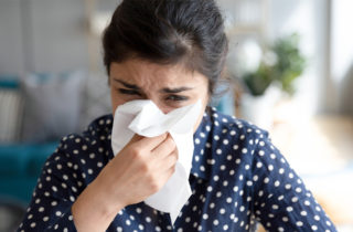 Ill, upset girl holding paper tissue blowing running nose, sneezing in handkerchief, got flu, fever, caught cold, influenza, sit at home, flu sinus, virus, disease symptom concept, face close up view