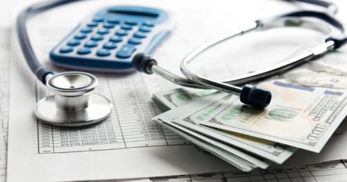 Medical expenses and paying for cancer treatment can be expensive. Image of a stethoscope, a bill, a calculator and cash.