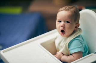 a coughing baby in highchair.