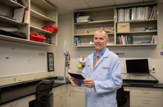 Christopher Zallek, MD, stands in the NeuroHealth Lab with a clipboard