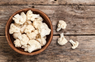 Pieces of cauliflower sitting in a wooden bowl. Cauliflower can be a healthy substitute for meal-time favorites.