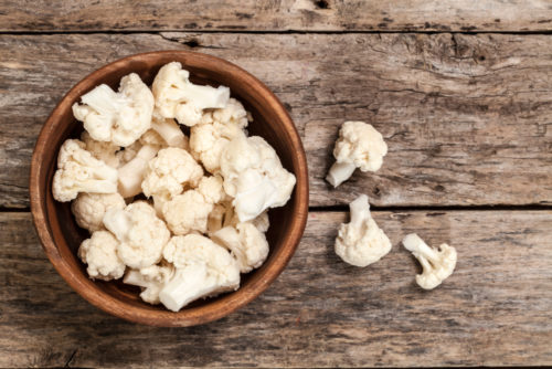 Pieces of cauliflower sitting in a wooden bowl. Cauliflower can be a healthy substitute for meal-time favorites.