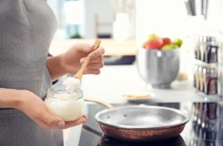 Woman putting coconut oil into a frying pan.