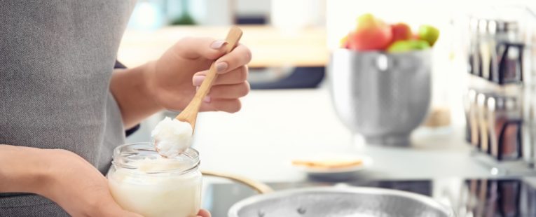 Woman putting coconut oil into a frying pan.