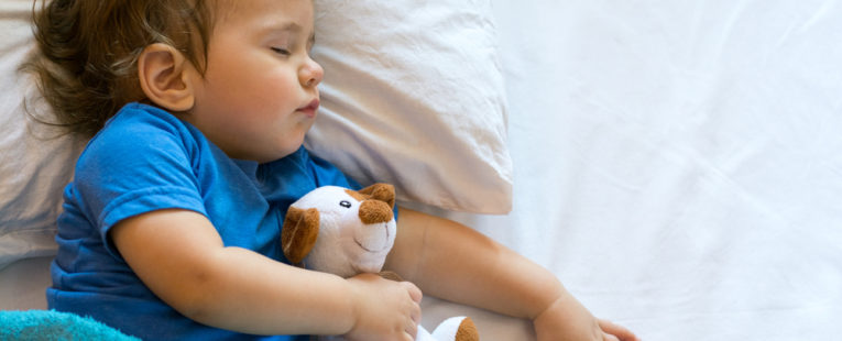 Young boy sleeping with stuffed animal.