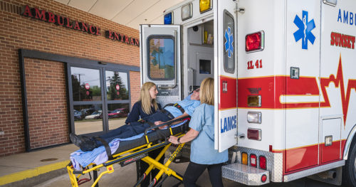 Man on stretcher being loaded into an ambulance by two women