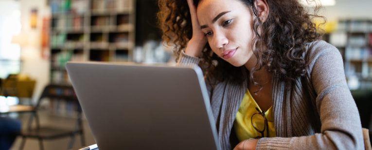 Woman with ADHD looks at her laptop with a pensive expression.