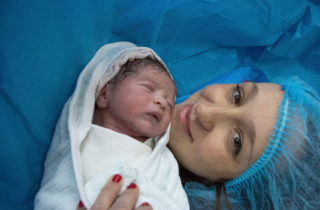 A mother and her baby smile after a c-section.