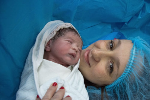 A mother and her baby smile after a c-section.