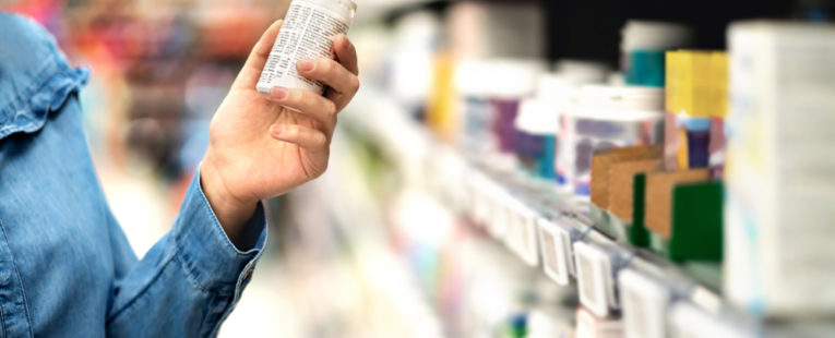 A customer looks at the labels of acetaminophen and ibuprofen.