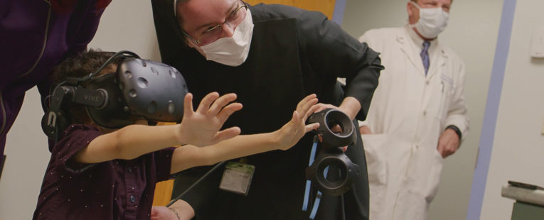 Sister Pieta and a child showcase the use of virtual reality.