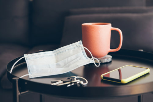 A mask sits on a coffee table next to keys and a cell phone, which brings up the question, is COVID-19 over?