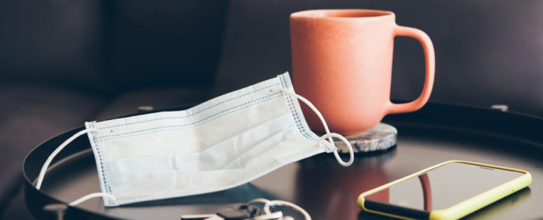 A mask sits on a coffee table next to keys and a cell phone, which brings up the question, is COVID-19 over?