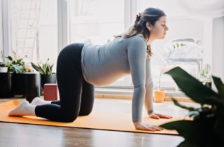 A woman stretches to safely exercise her pelvic floor muscles during pregnancy.