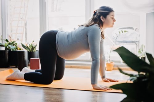 A woman stretches to safely exercise her pelvic floor muscles during pregnancy.