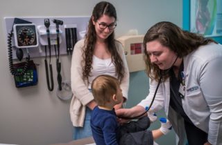 a provider examining a child at OSF OnCall Urgent Care; mother stands beside her child