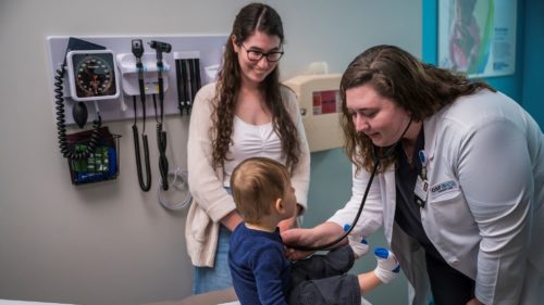 a provider examining a child at OSF OnCall Urgent Care; mother stands beside her child