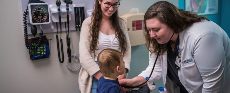 a provider examining a child at OSF OnCall Urgent Care; mother stands beside her child