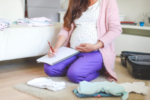 A pregnant woman sits down to write down her birth plan.